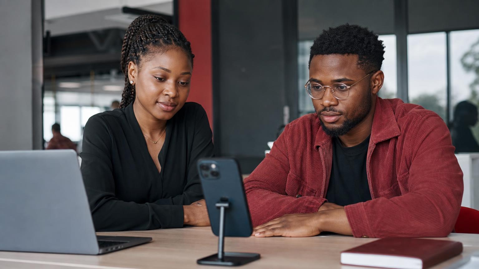 Young African engineers testing a mobile app on smartphones in a modern office